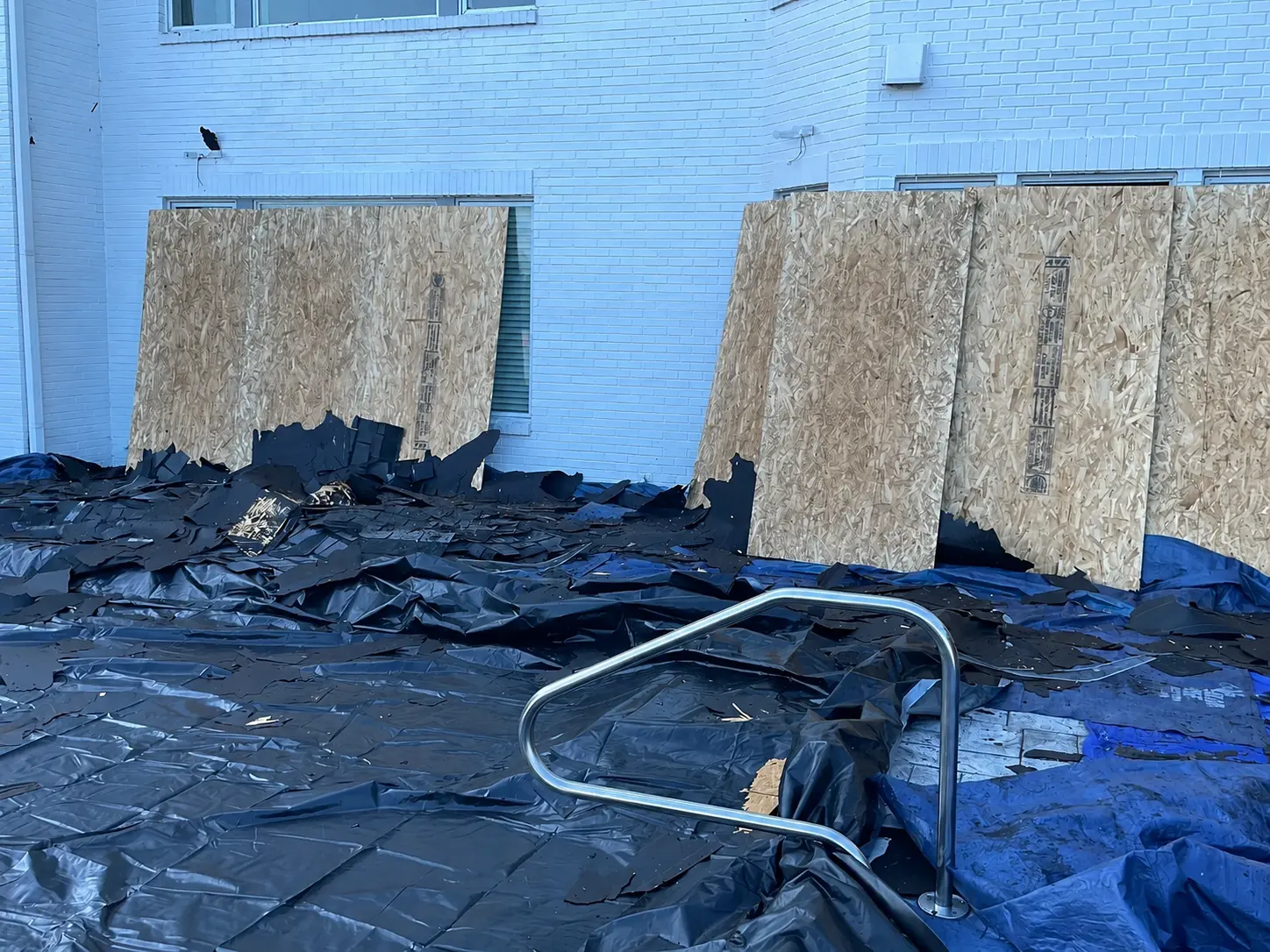 Plywood protection installed over windows and garage doors during a WRI roof replacement